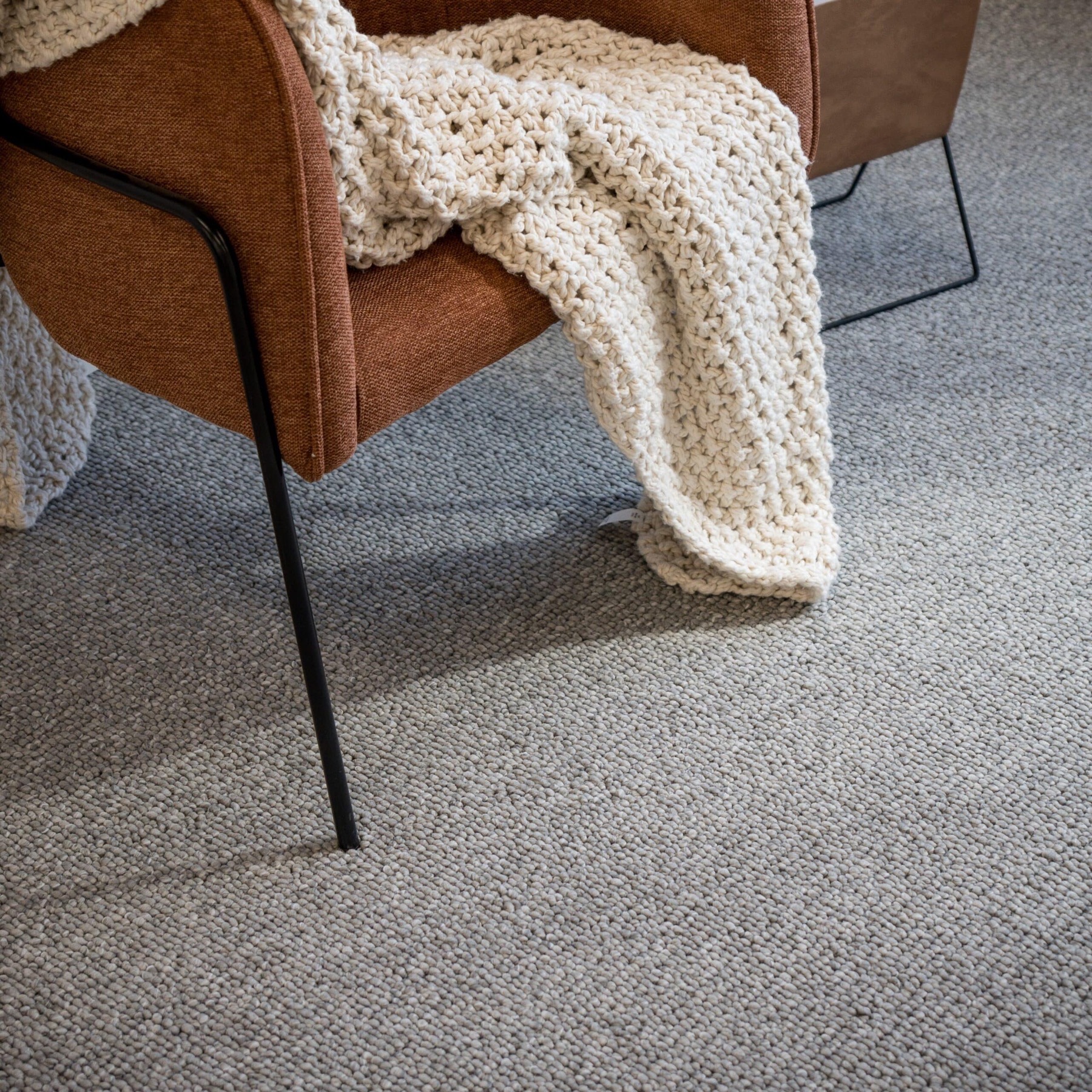 Tuscany Masa: a soft grey wool rug with a tan armchair and cream throw