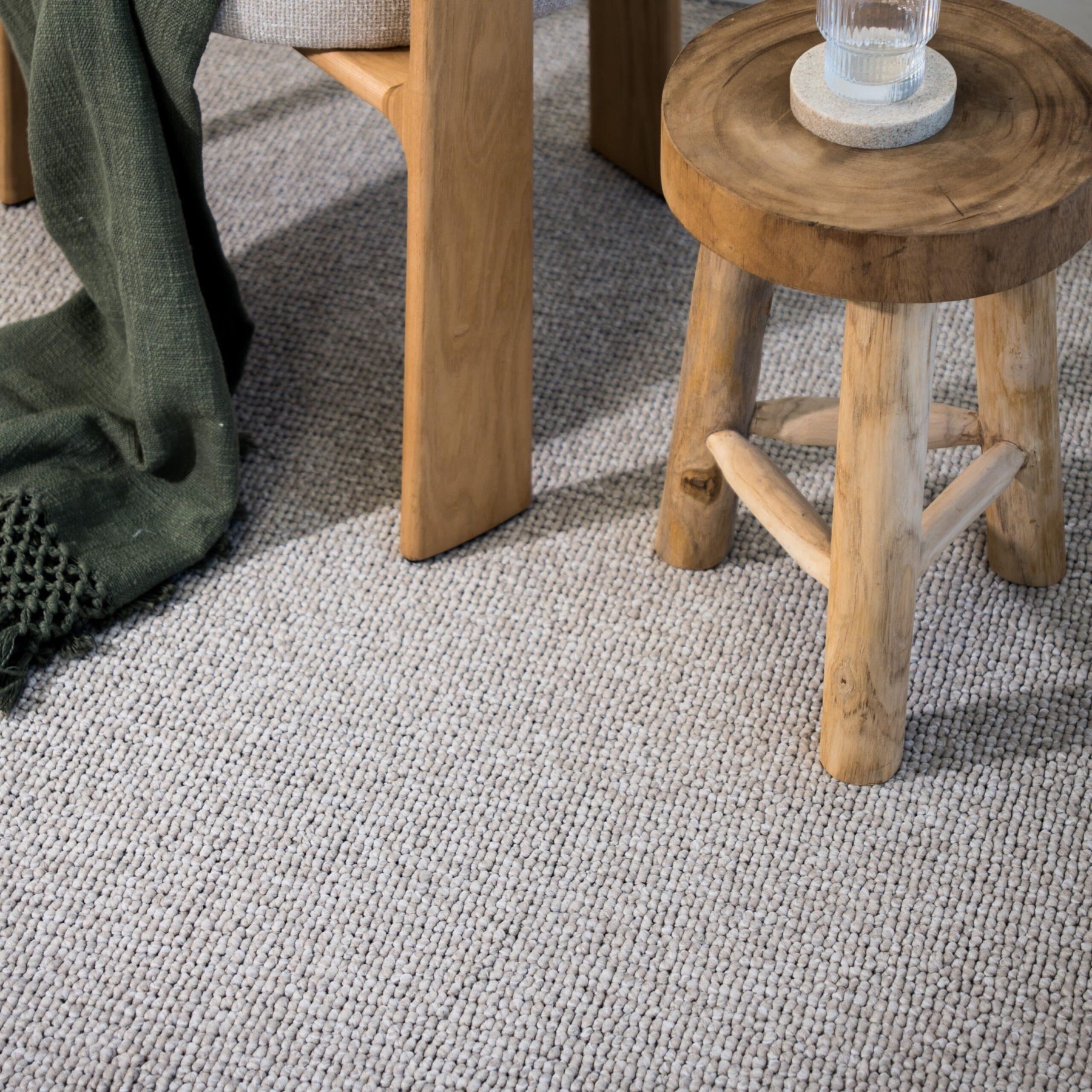 A neutral wool loop-pile rug in a calm, timeless room with a timber stool